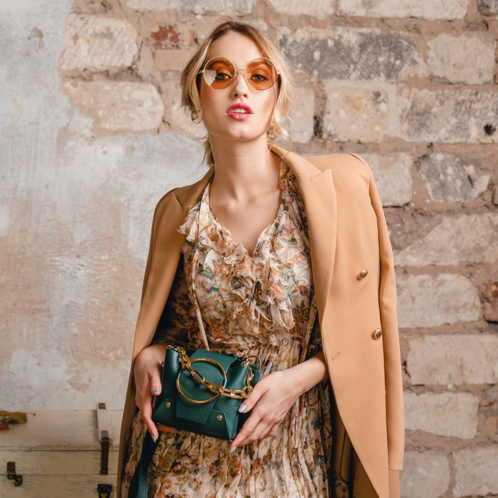 Woman holding a green handbag against a textured wall background