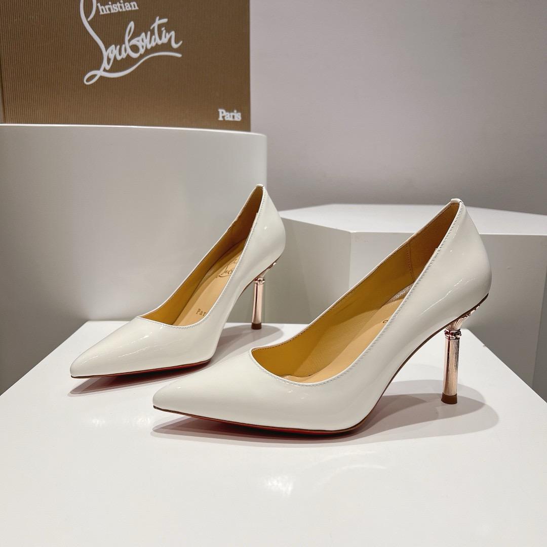 White high-heeled shoes with gold accents on a white platform, featuring the Christian Louboutin logo.